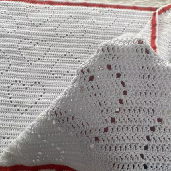 A romantic white crochet baby blanket made of breathable cotton yarn, with delicate heart-shaped patterns and a playful red edge – perfect for Valentine’s Day, springtime strolls, or newborn photo shoots. Soft, heirloom-worthy, and handmade with love.