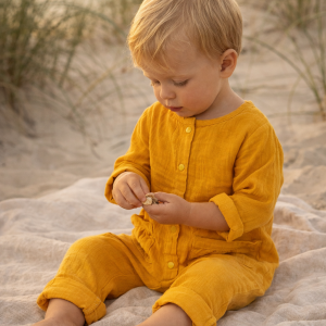 Baby Boy in a daisy color boho romper sitting on a beach