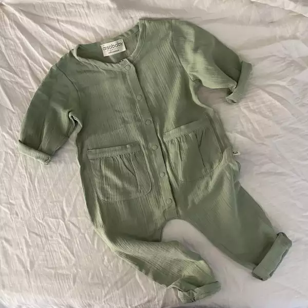 Handmade sage green baby romper made from soft organic muslin cotton. Breathable and stylish long-sleeve one-piece outfit for babies and toddlers – gender-neutral boho baby gift idea.
